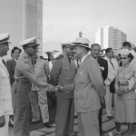O Capitão Marcílio Gibson Jacques cumprimenta o Ministro da Aeronáutica, Dr. Joaquim Pedro Salgado Filho. O Ten. Cel. Nero Moura aparece ao fundo entre eles, enquando à direita aparece sua esposa, Sra. Marieta Fabrício Moura.
 Foto: Arquivo Nacional.
